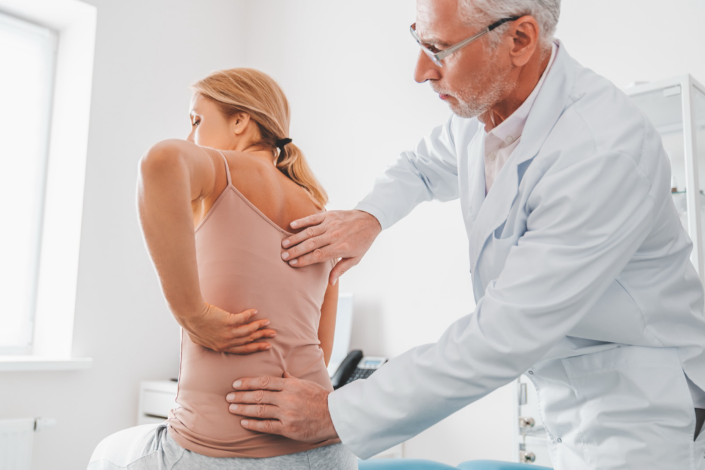 Physician examining a patient's lower back to find the cause of back pain after a car accident