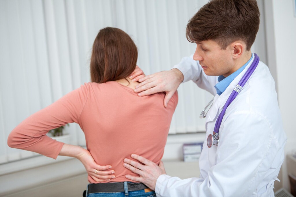 Doctor examining a patient's upper and lower back for injuries after a crash