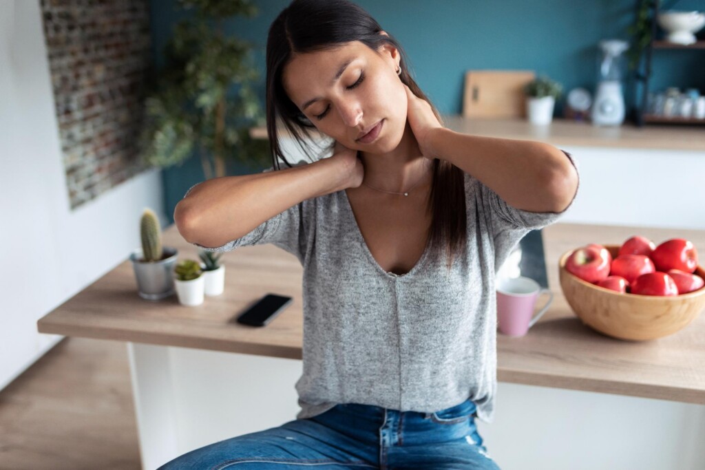 Woman at home holding her stiff neck days after a car accident