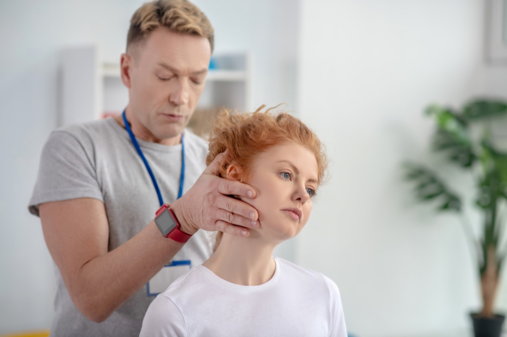 Clinician examining a patient's neck for whiplash, a common source of headaches after a car accident