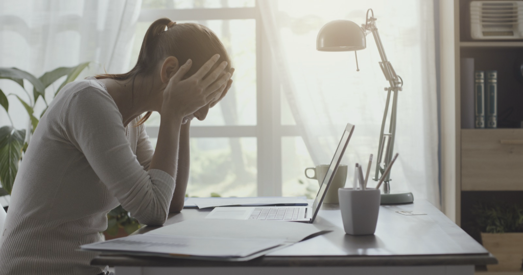 Woman at her desk holding her head, dealing with a headache after a car accident