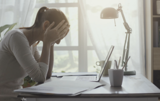 Woman at her desk holding her head, dealing with a headache after a car accident